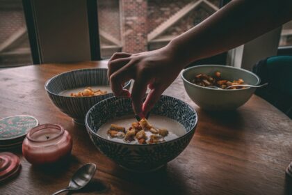 a person reaching for a spoon in a bowl of cereal; soup care packages