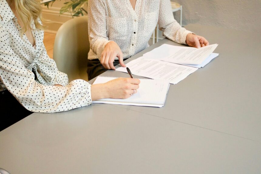 woman signing on white printer paper beside woman about to touch the documents; RMD rules