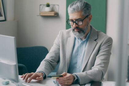 A man sitting at a desk using a laptop computer; 401(k) Catch-Up Contributions