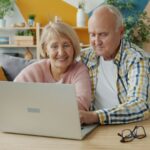 Elderly couple smiling while looking at laptop together; Social Security COLA