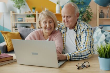Elderly couple smiling while looking at laptop together; Social Security COLA