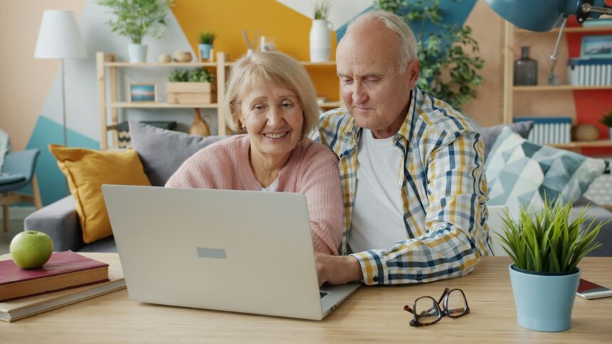 Elderly couple smiling while looking at laptop together; Social Security COLA