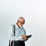A man in a dress shirt and suspenders holding a tablet; senior credit card debt