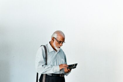 A man in a dress shirt and suspenders holding a tablet; senior credit card debt
