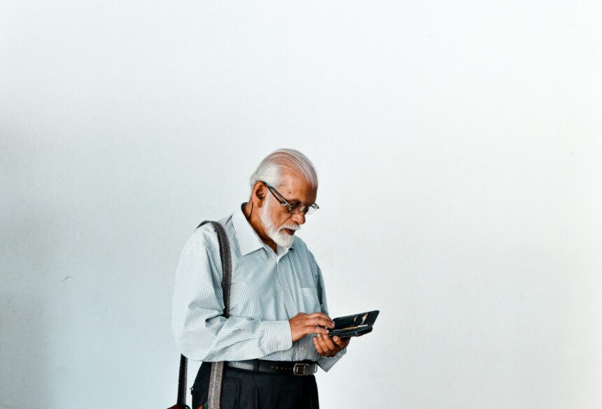 A man in a dress shirt and suspenders holding a tablet; senior credit card debt